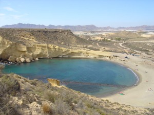 Panormica de la cala tomada desde La Carolina. Al fondo los acantilados de las areniscas pliocenas en cuya cima resaltan los conglomerados pliocenos